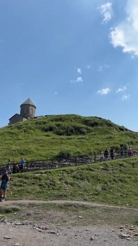 Hilltop church and grazing horse in Stepantsminda's mountain valley