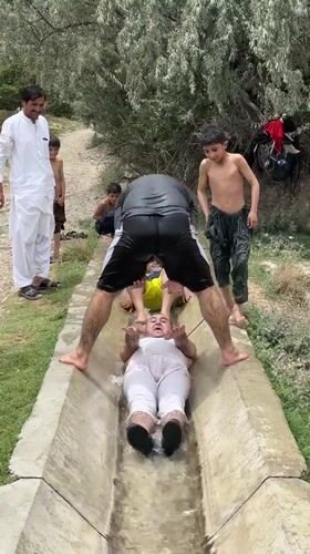 Group cools off in a concrete water channel in rural Pakistan