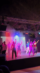 Choreographed dance performance on a colorlit outdoor stage in Sicily