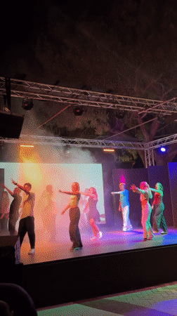 Choreographed dance performance on a colorlit outdoor stage in Sicily
