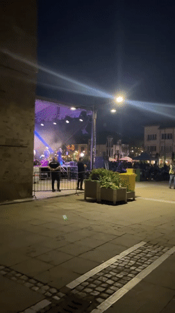 Outdoor night concert features band with colorful stage lighting