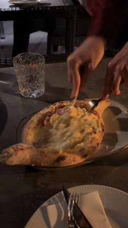 Diner enjoys Georgian khachapuri dish in Lisbon restaurant