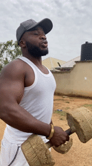 Man exercises with weights outdoors in rural Nigeria