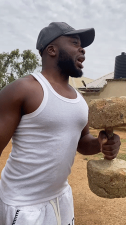 Man exercises with weights outdoors in rural Nigeria