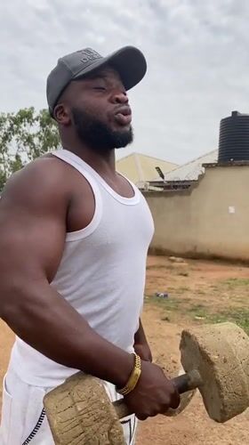 Man exercises with weights outdoors in rural Nigeria