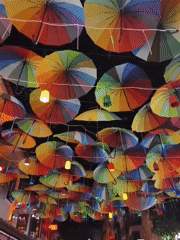 Kuşadası marketplace glows under lanterns and colorful umbrellas at night
