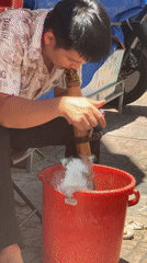 Man cleans bamboo pipe with water in Nha Trang