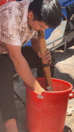 Man cleans bamboo pipe with water in Nha Trang