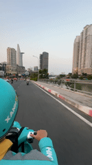 Scooter rider in blue-green gear travels Thủ Đức street