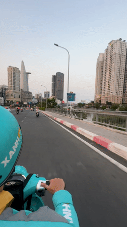 Scooter rider in blue-green gear travels Thủ Đức street