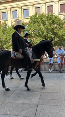 Horseback riders in traditional dress parade through Pamplona streets