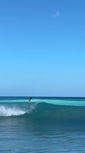 Surfers and beachgoers on a bright Kuta Selatan morning