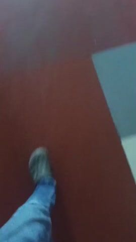 A video shows three people descending a set of stairs. The first person, wearing a dark shirt, is on the left side of the stairs. The second person, in a light-colored shirt, is in the middle. The third person, in a blue shirt, is on the right. The stairs appear to be indoors and have red carpeting with yellow markings on the edges of the steps. A metal railing runs along the side of the stairs. A window is visible at the top of the staircase. The video is shaky and the lighting is dim, making it difficult to discern fine details.