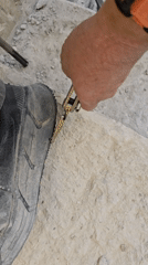 Person removes screw from stone surface in Ramat HaSharon