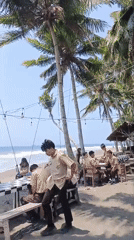 Groups gather at Batukaras beach on a clear sunny morning