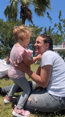 Woman shares moment with child on grass in Haifa