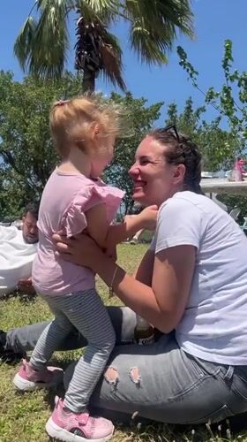 Woman shares moment with child on grass in Haifa