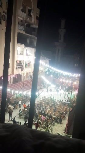 Nighttime community gathering illuminated by festive lights in Khan Yunis