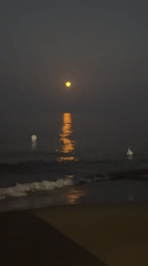 Full moon rising over calm Sardinian coastal waters