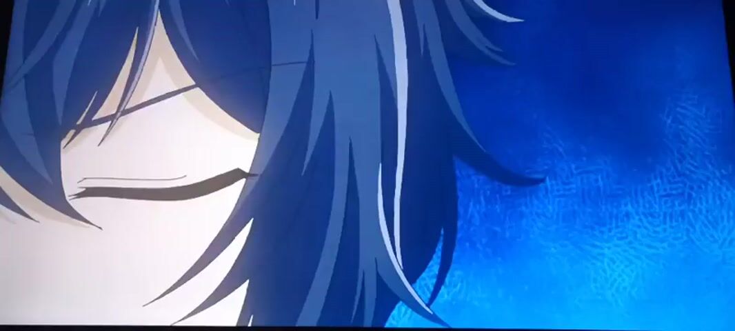 The video begins with a close-up of an anime character's eye, which is partially obscured by dark blue hair. The eye opens, revealing a purple iris. The scene then transitions to a wide shot of a brick-like court, possibly for a sport, with white lines marking the boundaries. A decorative emblem is visible in the center of the court. A figure in a dark blue coat is standing on the right side of the court. The character's eye appears again in a close-up with a purple iris and dark blue hair, looking intently.
