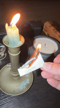 Person burns card with text over candle in Cape Town