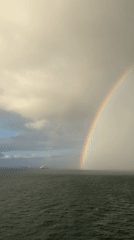 Double rainbows spotted over ocean waters with maritime traffic