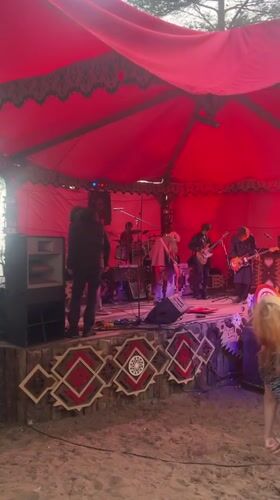 Live band plays under a red tent with full instrumentation