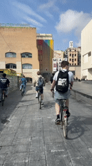 Young cyclists ride through Barcelona plaza amid street art