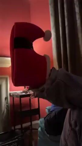 A person holds a red Santa hat-shaped bag toward the camera. The camera pans over to a woman lying on a couch looking at her phone.