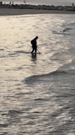 Metal detector enthusiast searches Tel Aviv beach waters