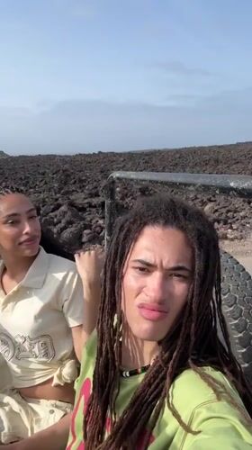 Couple rides open vehicle through volcanic terrain near Tinajo