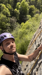 Rock climber with cow-stickered helmet scales grey cliffs in Bulgaria