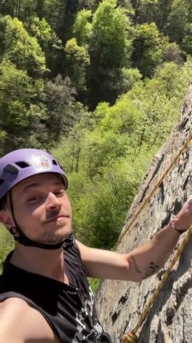 Rock climber with cow-stickered helmet scales grey cliffs in Bulgaria