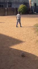 Boy examines rock stack in dirt field, Jos