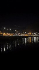 Nighttime harbor lights illuminate A Coruña waterfront scene