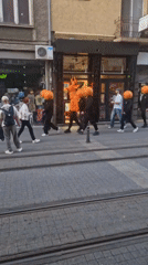 Group in pumpkin costumes walks city streets near tramway