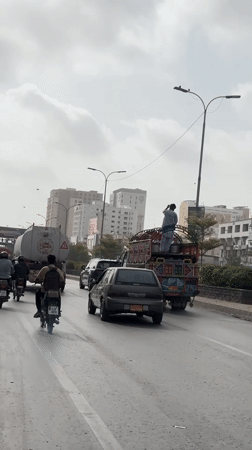 Motorcycle weaves through mixed traffic on a Karachi street