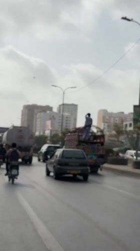 Motorcycle weaves through mixed traffic on a Karachi street