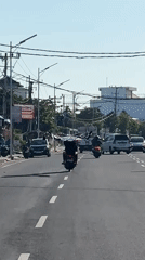 Motorcyclist carries large fabric through North Kuta intersection
