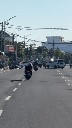 Motorcyclist carries large fabric through North Kuta intersection