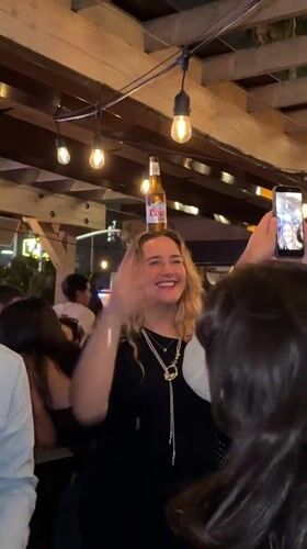 Woman balances beer bottle on head at San Diego bar