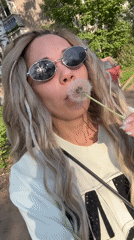 Woman enjoys sunny afternoon blowing dandelions, taking selfies outdoors