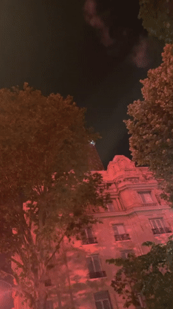 Red fireworks light up Paris sky near Eiffel Tower