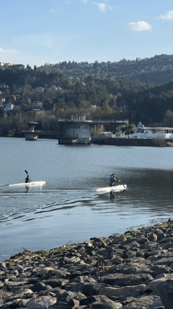 Two kayakers paddle across calm lake in Pancharevo, Bulgaria