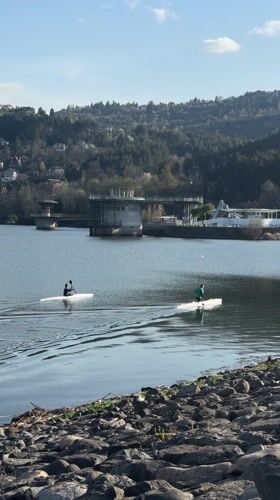 Two kayakers paddle across calm lake in Pancharevo, Bulgaria