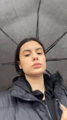 Woman with umbrella walks wet streets in Chaikovsky