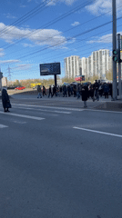 Pedestrians cross busy street while child rides unusual vehicle