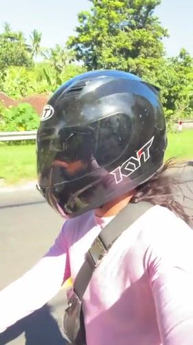 Motorcyclist rides through tropical road in Manggis, Indonesia
