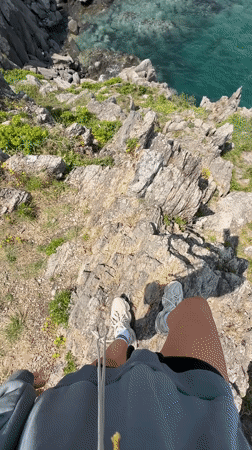 Visitors gather at scenic Russian coastal cliffs overlooking turquoise bay