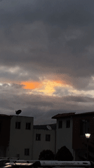 Orange light breaks through cloudy evening sky in Quito